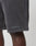 A close-up of a persons legs in dark gray Basic Heavy Shorts by LIVE FAST DIE YOUNG, featuring a LiveFastDieYoung logo print near the hem against a plain, light-colored background.