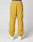 Model wearing LIVE FAST DIE YOUNG LFDY Trackpants in mustard yellow with elastic waistband and cuffs, paired with white sneakers. Photo shows the loose polyester fit from the back against a plain white background.