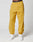 Someone stands against a white background wearing mustard yellow LFDY Trackpants by LIVE FAST DIE YOUNG with an elastic waistband and reflective print, paired with white sneakers and black LIVE FAST branded underwear.