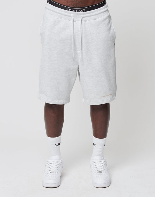 A person wears LIVE FAST DIE YOUNG Basic Heavy Shorts in light gray, regular fit, knee-length with an elastic waistband, white LIVE FAST socks and sneakers, against a plain white background.