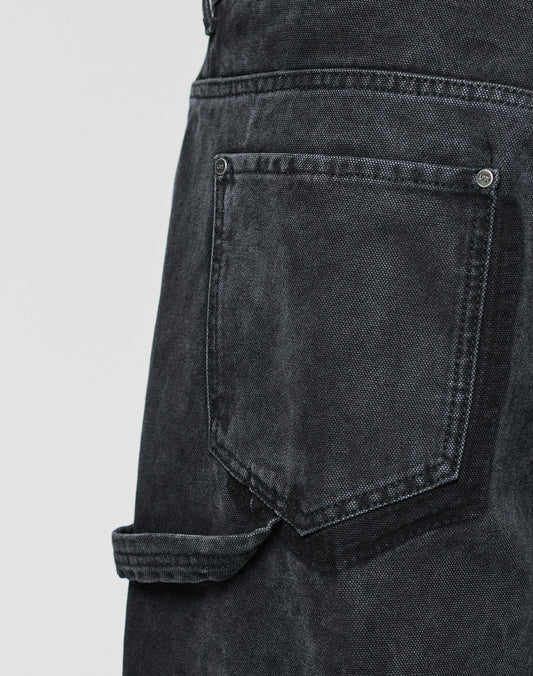 Close-up of the LFDY Carpenter Pants by LIVE FAST DIE YOUNG in black denim, featuring visible stitching and a strap below the pocket for a classic carpenter look against a plain, light gray background.