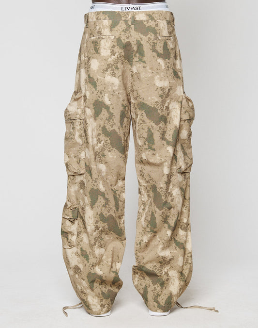 A person wearing LIVE FAST DIE YOUNGs LFDY Cargo loose, wide-fit camouflage cargo pants with multiple pockets and ankle drawstrings, standing against a plain white background.