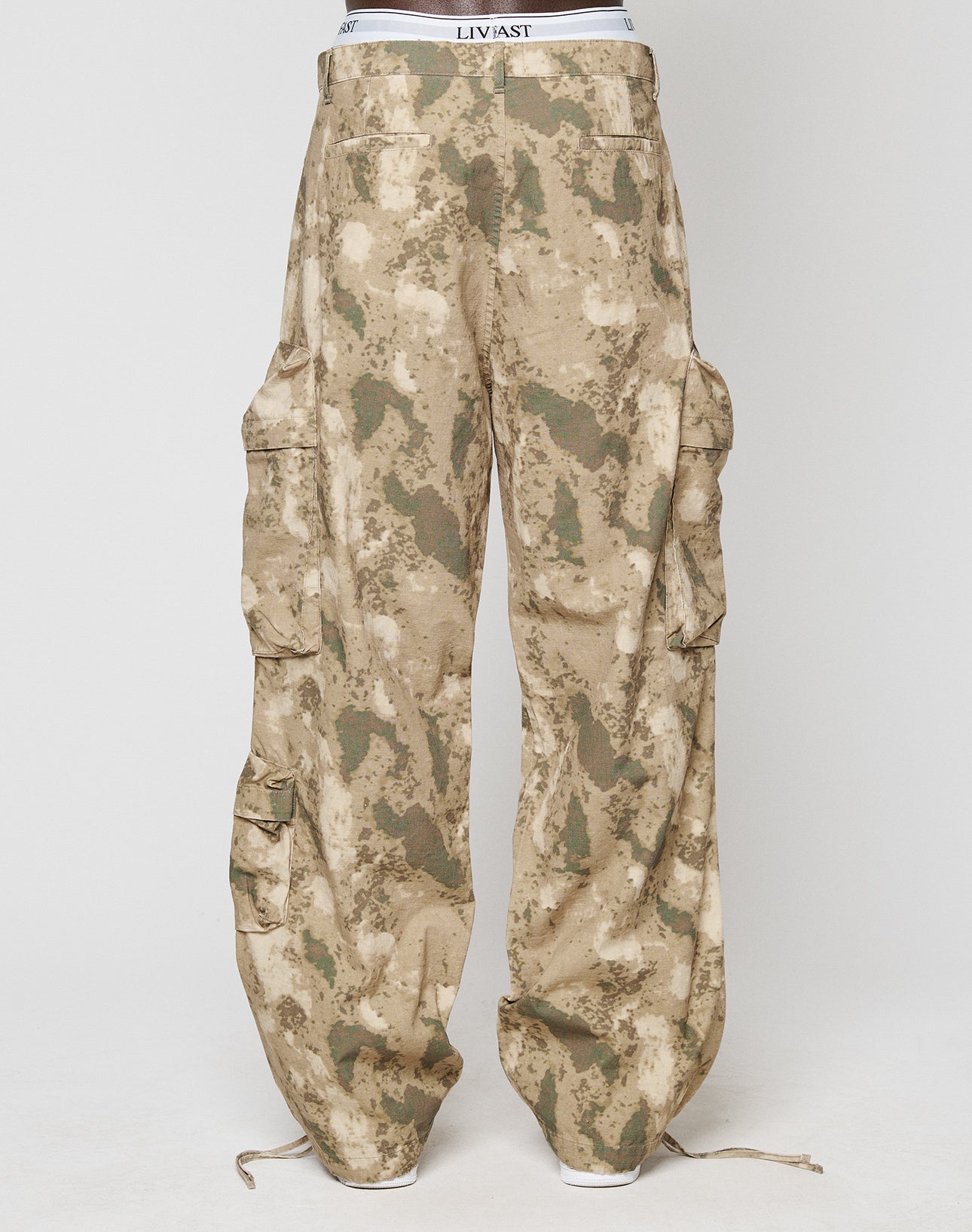 A person wearing LIVE FAST DIE YOUNGs LFDY Cargo loose, wide-fit camouflage cargo pants with multiple pockets and ankle drawstrings, standing against a plain white background.
