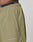Close-up of a person wearing LIVE FAST DIE YOUNGs Live Fast Trackpants in light olive green. Wide Fit, white LIVE FAST near the pocket, black waistband with matching phrase, and an elastic drawcord for adjustable comfort.