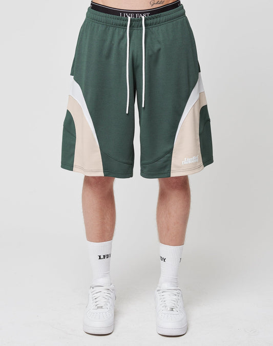 A person wearing LIVE FAST DIE YOUNG Basic Trackshorts in green, white, and beige 100% polyester, paired with LFDY logo-print white socks and white sneakers, stands against a plain white background. Only the lower body is shown.