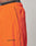 Close-up of a person wearing bright orange Live Fast Trackpants by LIVE FAST DIE YOUNG. The pants feature black piping, a reflective logo print and LIVE FAST branding near the pocket, plus a wide elastic waistband for comfort.