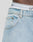 Close-up of a person wearing LFDY Baggy Denim jeans from LIVE FAST DIE YOUNG, with a focus on the pocket and waistband area where white underwear with black stripes and partial black text is visible.