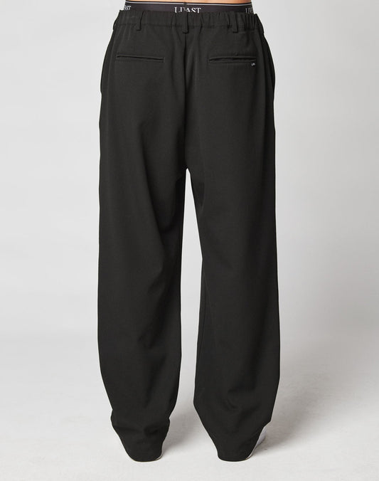 A pair of black LIVE FAST DIE YOUNG Wide Casual Pants with a loose fit, elastic waistband, and two back welt pockets, shown against a plain light background.