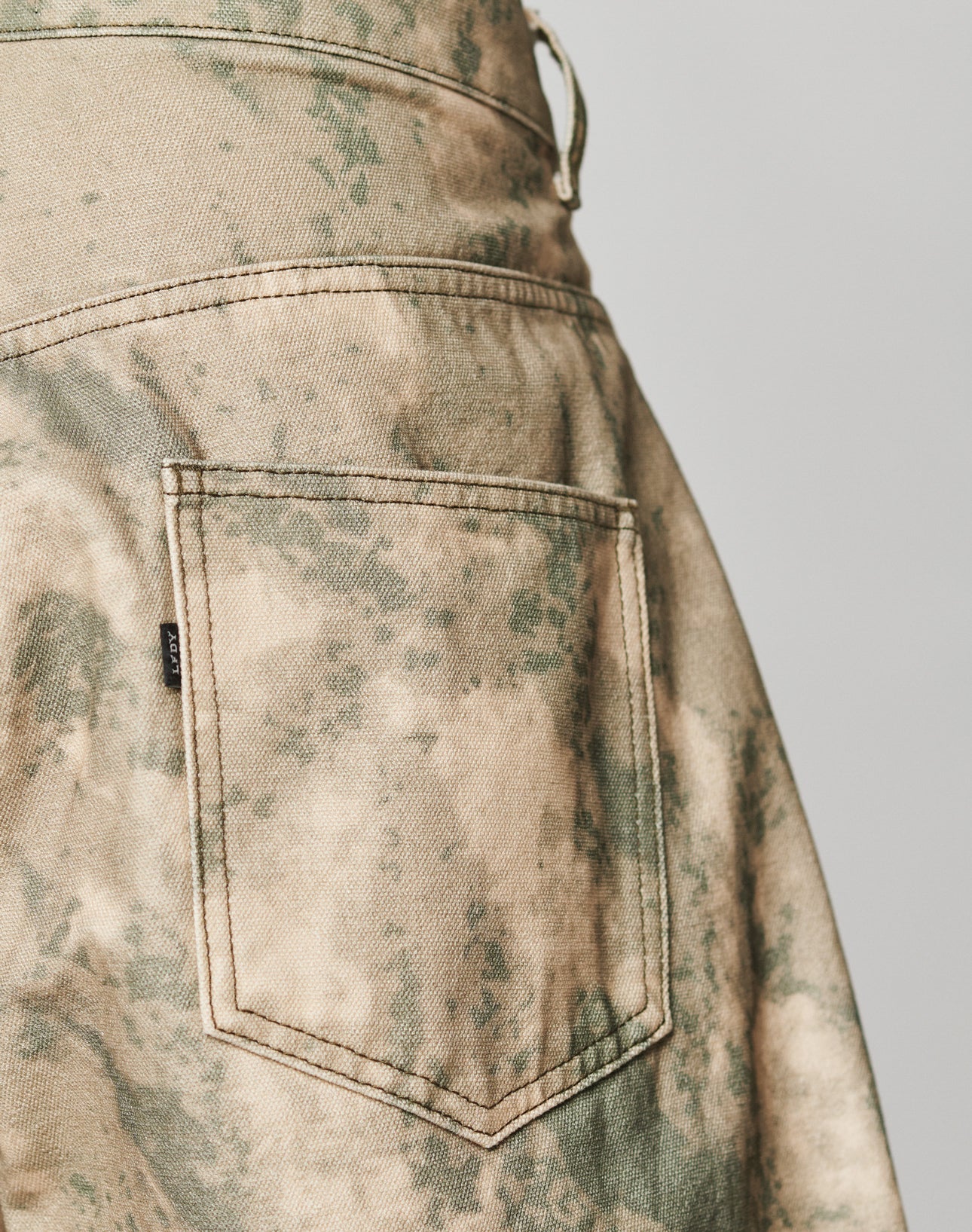 Close-up of the back pocket on LIVE FAST DIE YOUNGs Live Fast Canvas Pants, featuring green and beige camo, detailed stitching, and 100% Baumwolle fabric for a comfortable baggy fit.