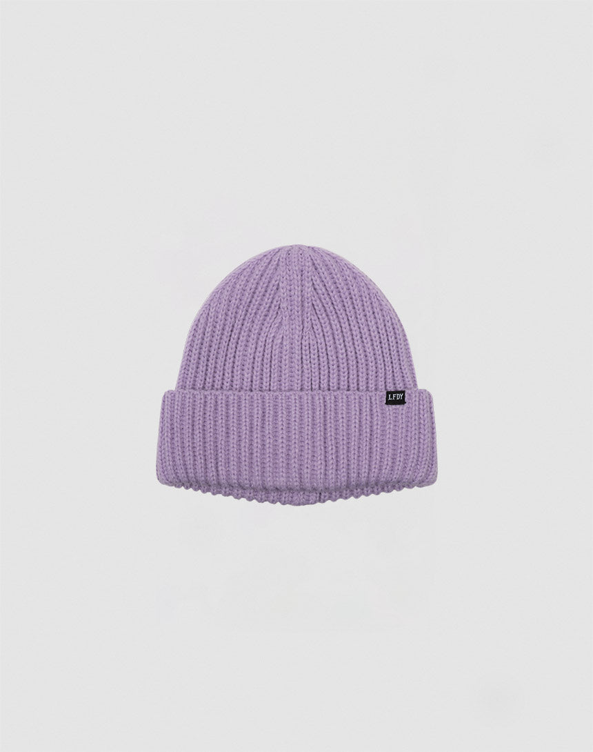 The LIVE FAST DIE YOUNG Rib Knit Beanie is a light purple Polyacryl beanie with a ribbed knit, folded brim, and a small black rectangular tag on the front, shown on a plain white background.
