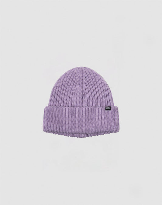 The LIVE FAST DIE YOUNG Rib Knit Beanie is a light purple Polyacryl beanie with a ribbed knit, folded brim, and a small black rectangular tag on the front, shown on a plain white background.