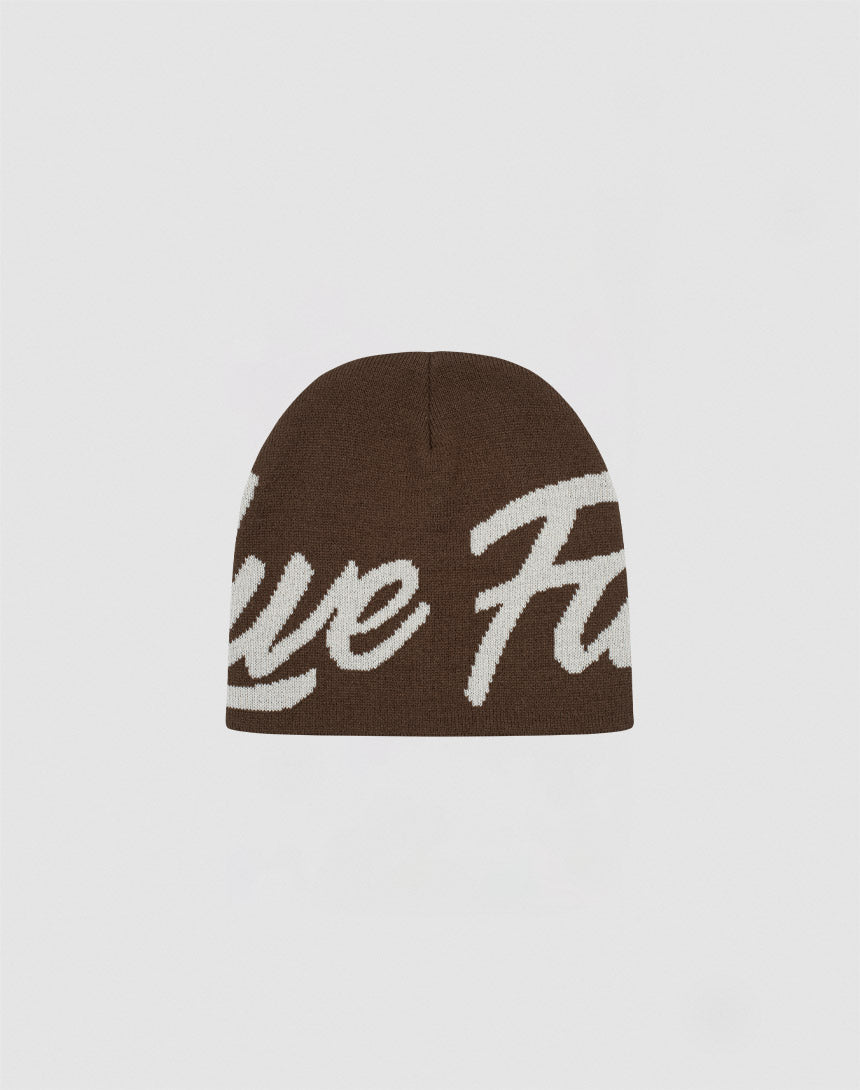 The LFDY Jacquard Beanie by LIVE FAST DIE YOUNG is a brown Polyacryl knit hat with large white cursive logo lettering on the front, shown against a plain light background.