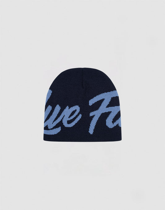 The LFDY Jacquard Beanie by LIVE FAST DIE YOUNG features navy blue Polyacryl knit, large light blue cursive logo across the front, and is shown on a plain light grey background. Part of the LF2410-16544 Logo Strick collection.