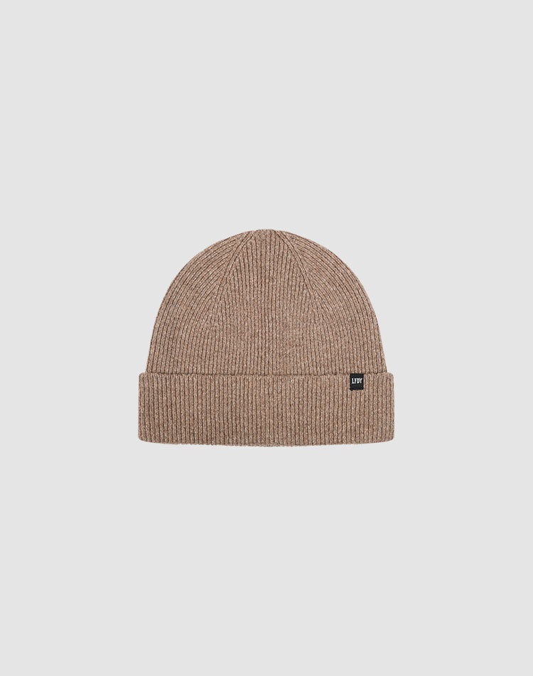 The Live Fast Boucle Beanie by LIVE FAST DIE YOUNG is a light brown ribbed polyester beanie with a folded brim and a small black flag-label on the front, shown against a plain light gray background.