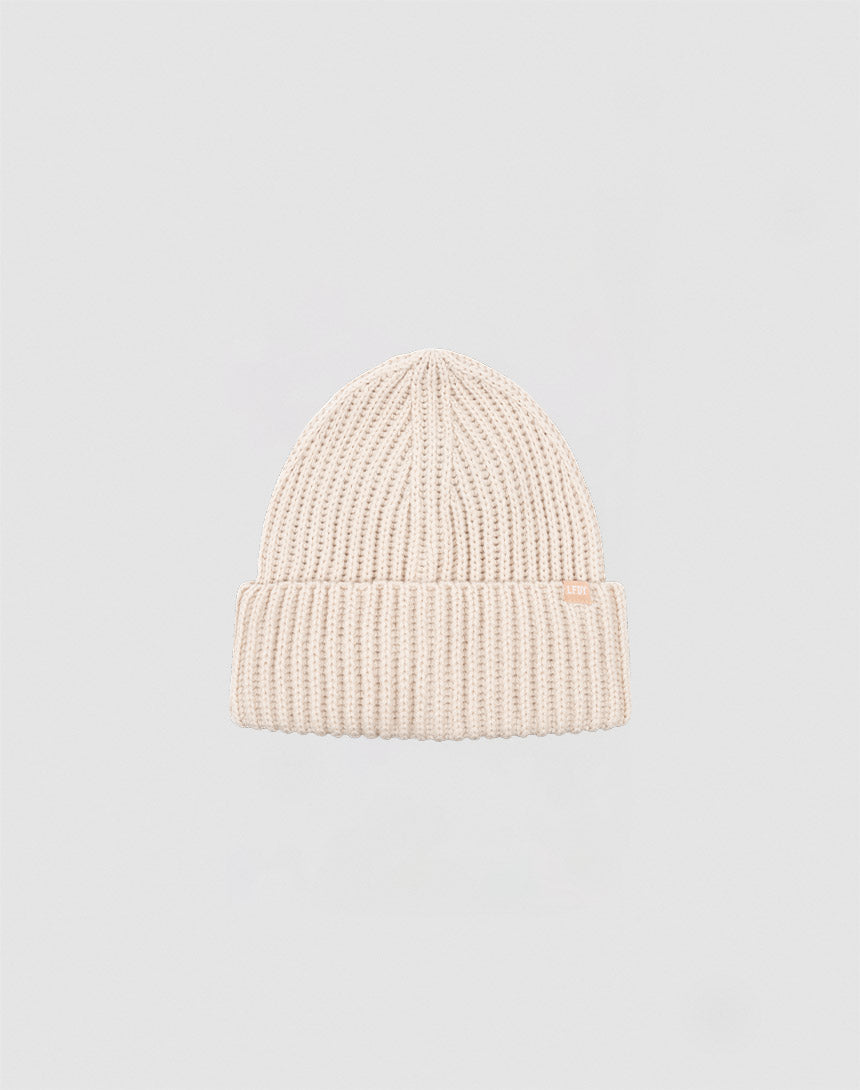 A beige Rib Knit Beanie aus Polyacryl von LIVE FAST DIE YOUNG mit umgeschlagenem Bund vor schlichtem hellgrauem Hintergrund.