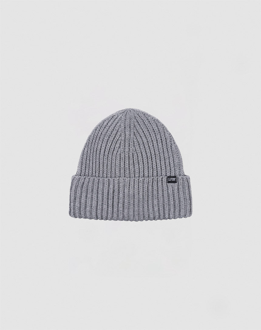 The LIVE FAST DIE YOUNG Rib Knit Beanie in grey is crafted from soft polyacryl, featuring a folded brim and a small black rectangular front tag, shown against a plain white background.