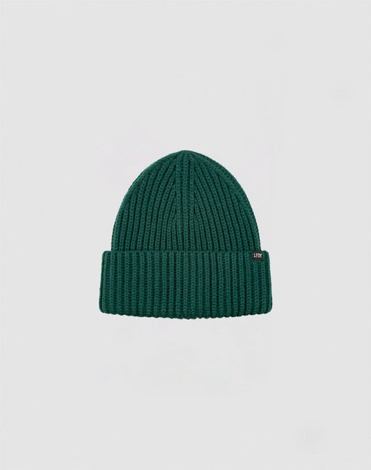 A LIVE FAST DIE YOUNG Rib Knit Beanie in green, featuring a folded brim with a small rectangular flag label, is centered on a plain light gray background.