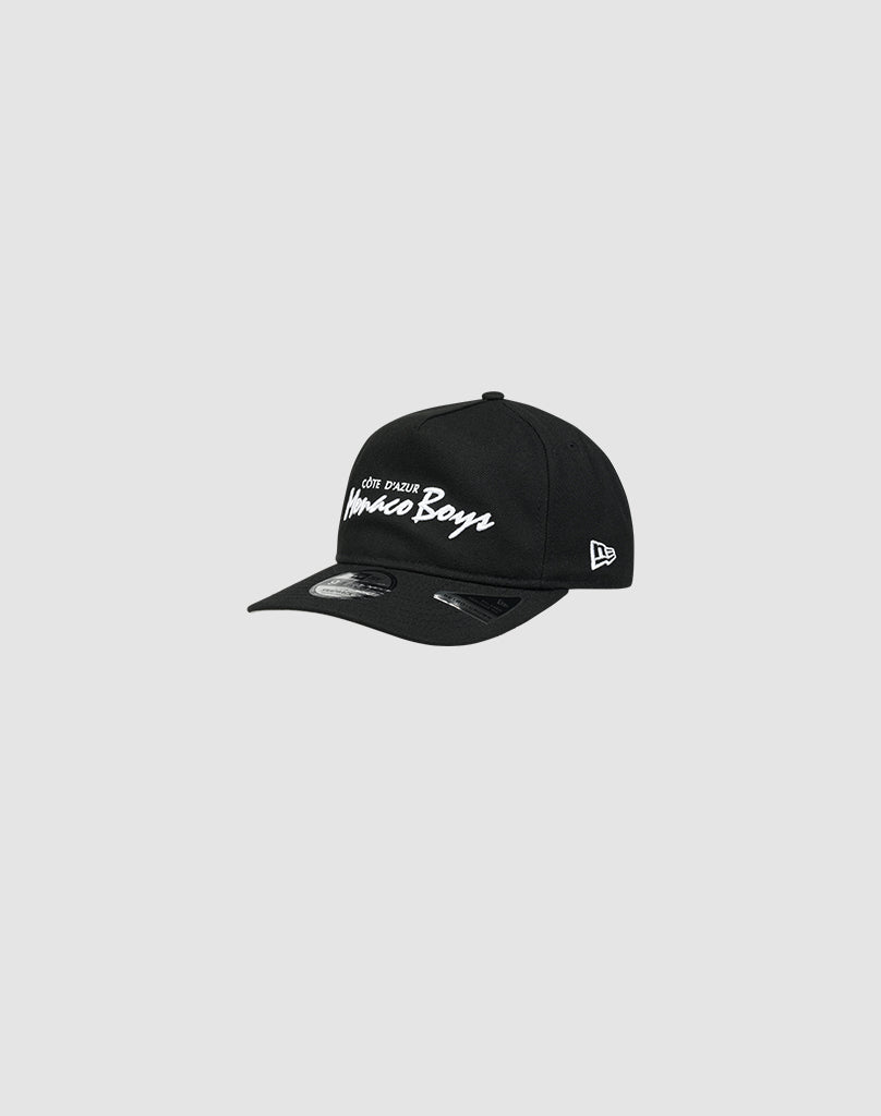 A LFDY X NEW ERA Monaco Boys black cap by LIVE FAST DIE YOUNG with white embroidered text on the front and the New Era Flag, shown on a light gray background.