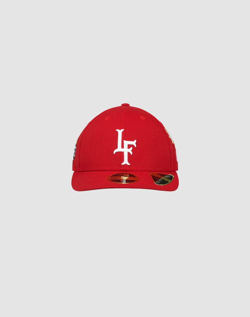 LFDY X NEW ERA 59FIFTY Low Profile fitted cap by LIVE FAST DIE YOUNG shown in red on a light gray background, with a white embroidered L F logo on the front and a shiny sticker on the flat brim. 