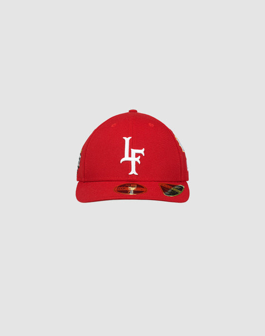 LFDY X NEW ERA 59FIFTY Low Profile fitted cap by LIVE FAST DIE YOUNG shown in red on a light gray background, with a white embroidered L F logo on the front and a shiny sticker on the flat brim.