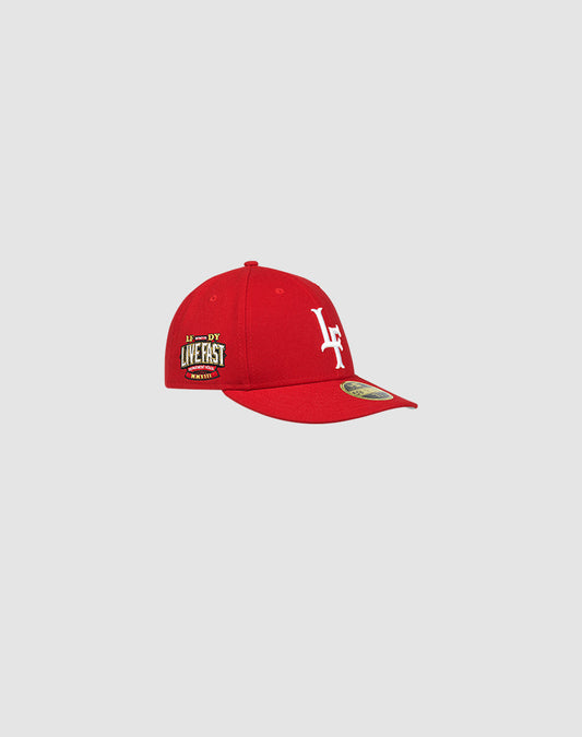 The LFDY x New Era 59FIFTY Low Profile fitted cap by LIVE FAST DIE YOUNG is red, with a white LF logo on the front and a yellow LIVE FAST side patch, shown against a plain light gray background.
