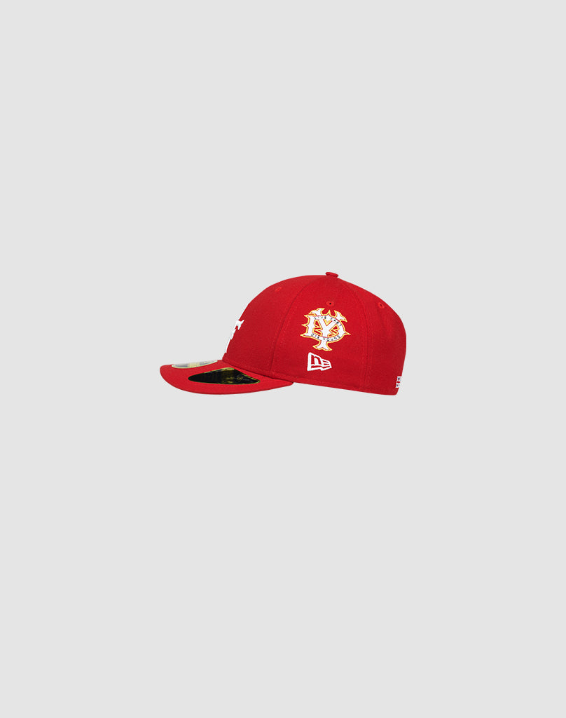 The LFDY X NEW ERA 59FIFTY Low Profile cap by LIVE FAST DIE YOUNG features red fabric, white and gold front embroidery, a flat brim, and a white New Era side logo, shown against a plain light gray background.