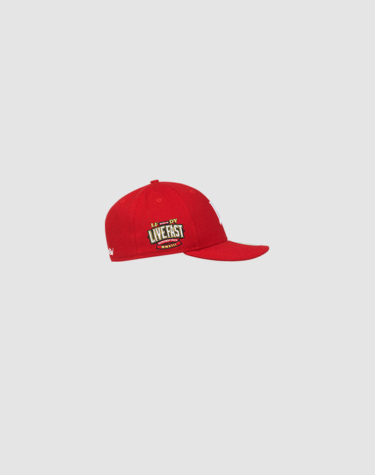 The LFDY X NEW ERA 59FIFTY Low Profile by LIVE FAST DIE YOUNG is a red fitted cap with a flat brim and yellow and white LIVE FAST embroidery on the side, shown against a plain light gray background.