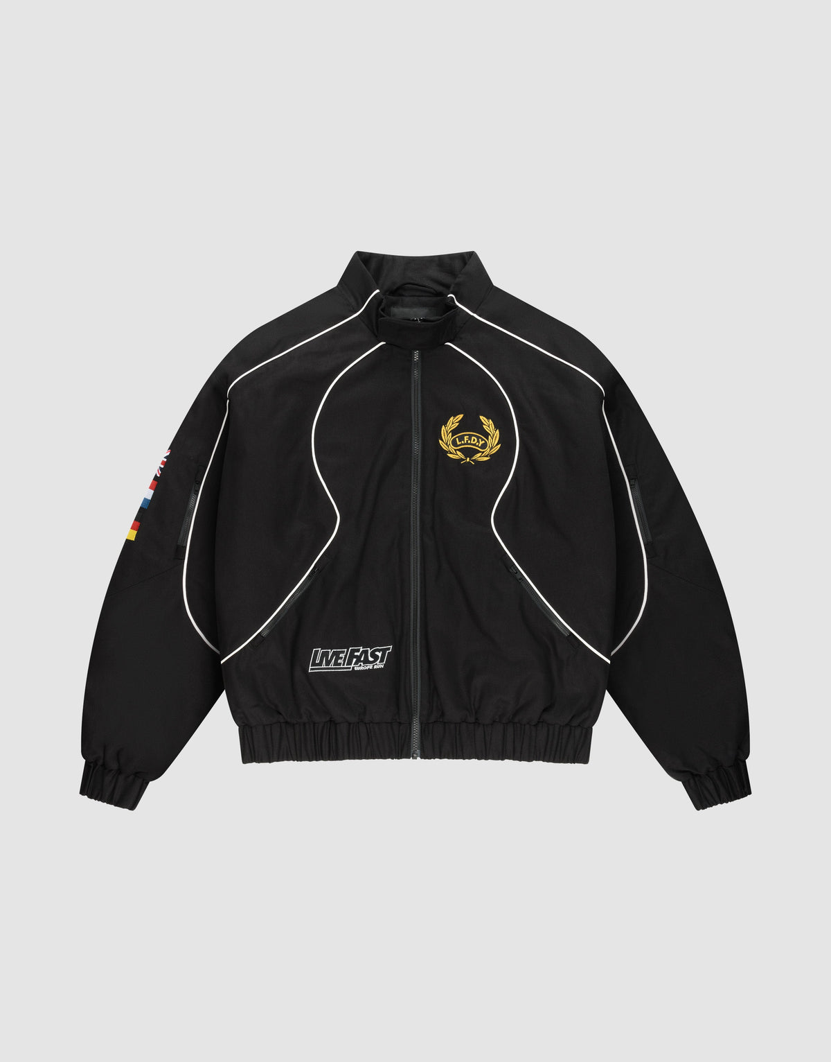 The LFDY Canvas Jacket by LIVE FAST DIE YOUNG is a black regular-fit zip-up with white piping, gold crest on the left chest, flag patches on the right sleeve, Multilogo Stickereien, and a "LIVE FAST" text patch near the left pocket. | plain