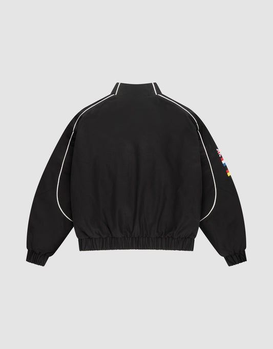 The LFDY Canvas Jacket by LIVE FAST DIE YOUNG is black with white piping on the sleeves and shoulders, multilogo flag patches on the right sleeve, elastic cuffs and hem, displayed on a plain light gray background.