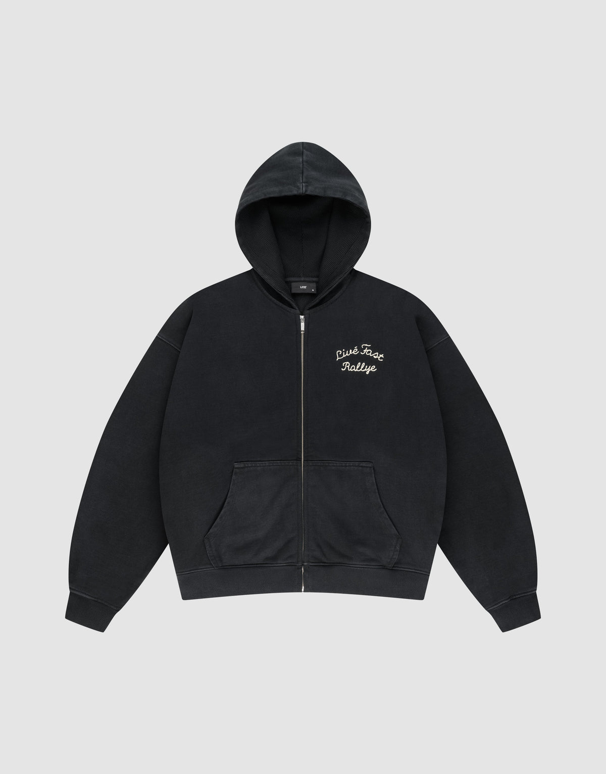 The LFDY L’Équipe Hooded Zip by LIVE FAST DIE YOUNG is a black oversized hoodie with a front pocket, hood, cozy waffle innenfutter, and white embroidered "Pink Face Rallye" text on the left chest. Laid flat on light gray background.