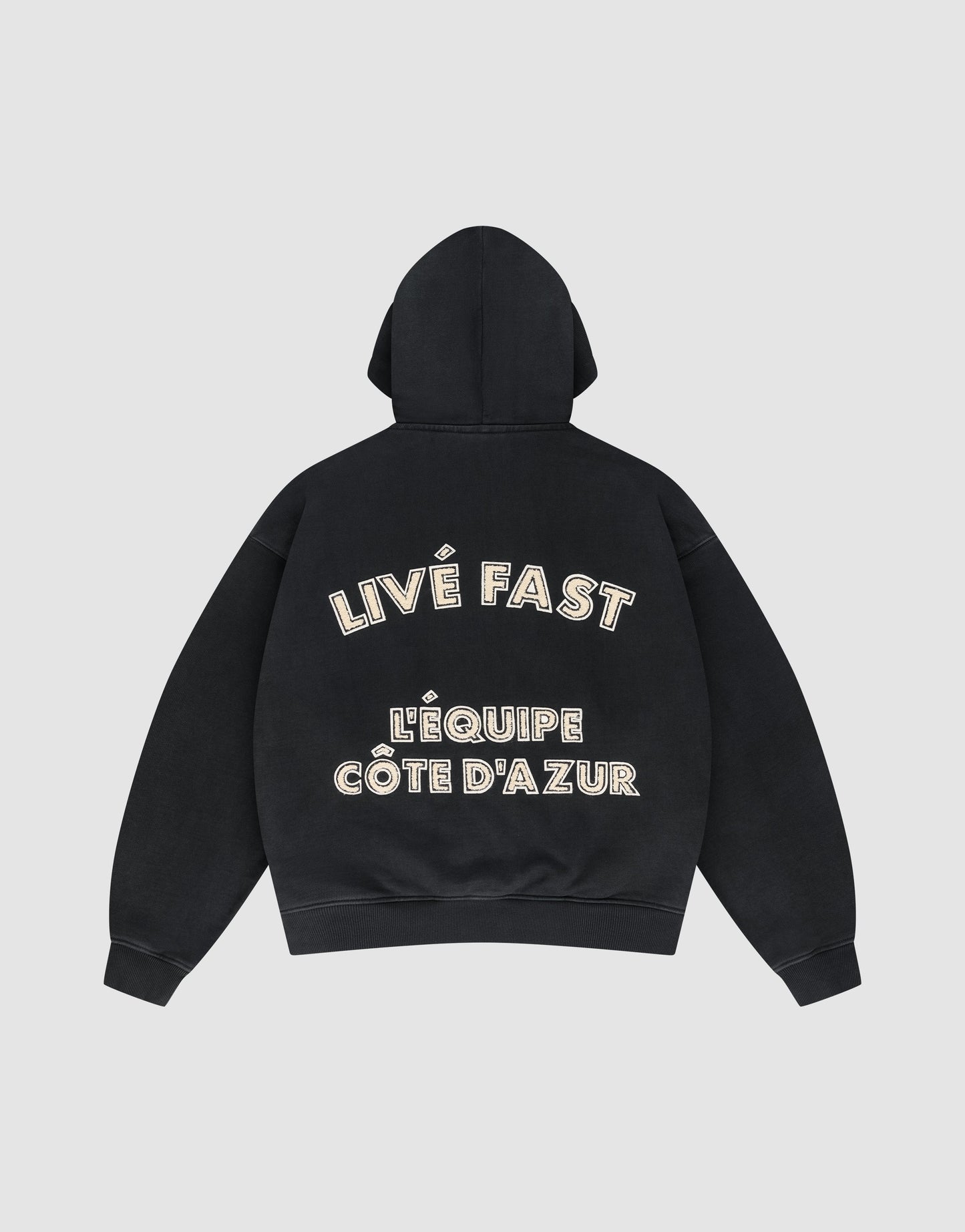 The LFDY L'Équipe Hooded Zip by LIVE FAST DIE YOUNG is a black oversize hoodie with LIVE FAST and LÉQUIPE CÔTE DAZUR in bold white lettering on the back, plus a soft waffle lining for extra comfort.