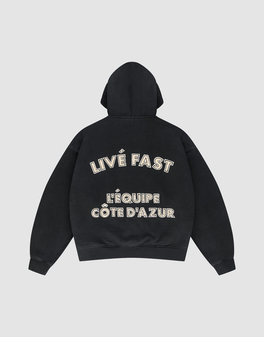 The LFDY L'Équipe Hooded Zip by LIVE FAST DIE YOUNG is a black oversize hoodie with LIVE FAST and LÉQUIPE CÔTE DAZUR in bold white lettering on the back, plus a soft waffle lining for extra comfort. | plain