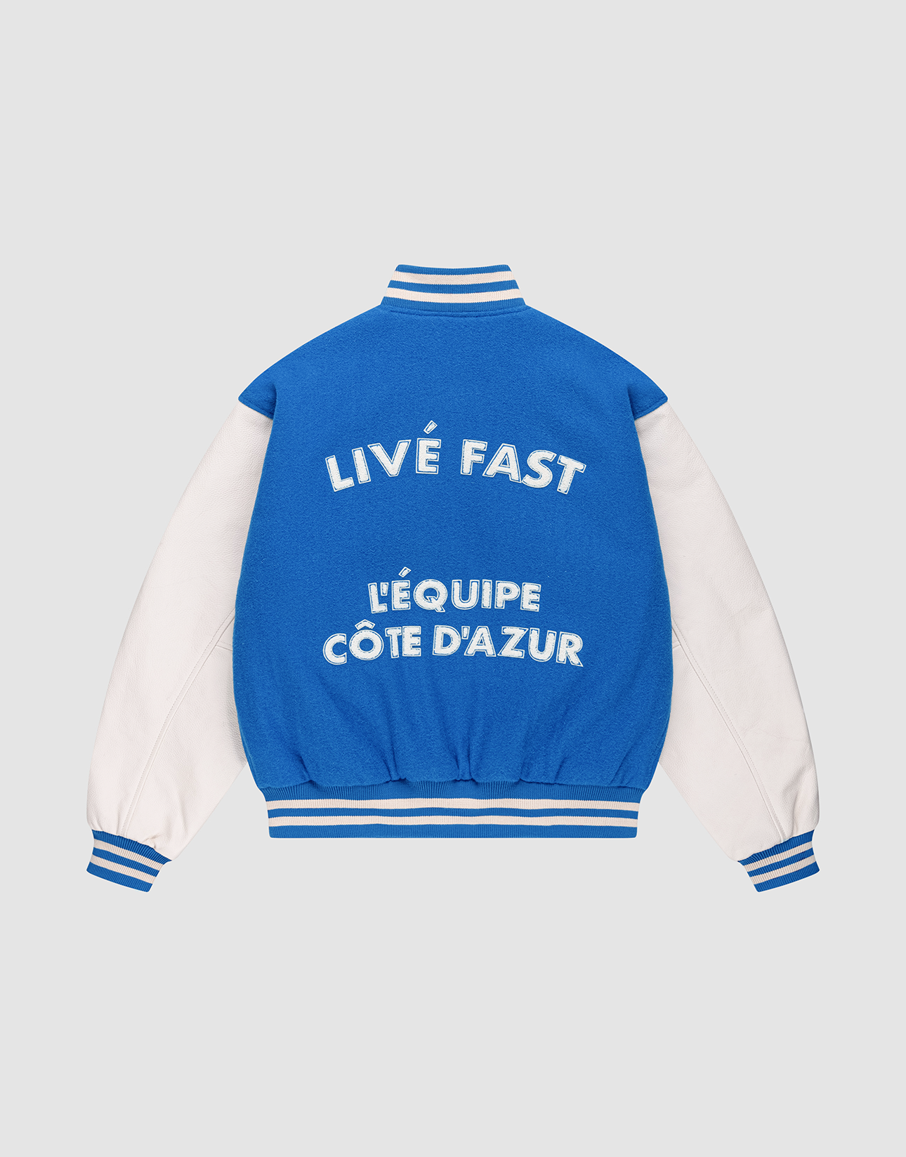 The LFDY x Schott NYC Varsity Jacket by LIVE FAST DIE YOUNG features blue and white colors, striped cuffs, collar, and hem. Bold text on the back reads LIVE FAST and LÉQUIPE CÔTE DAZUR on this limited edition piece with signature details.
