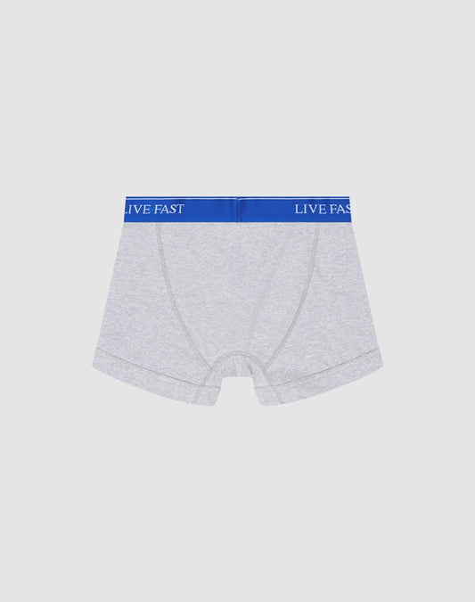 A pair of light gray Live Fast Trunks by LIVE FAST DIE YOUNG in Regular Fit, made of soft cotton with a blue elastic waistband reading LIVE FAST in white, shown on a plain white background.