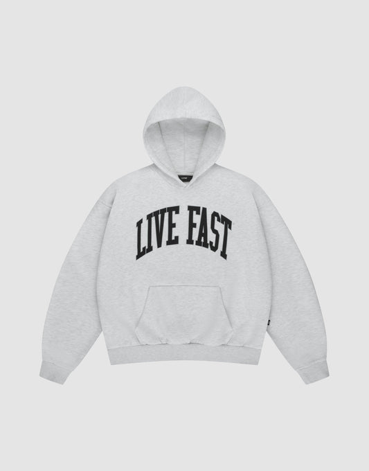 The LIVE FAST DIE YOUNG Live Fast College Hooded is a light gray hoodie with bold black "LIVE FAST" lettering across the chest, long sleeves, and a front pocket, shown on a plain white background.