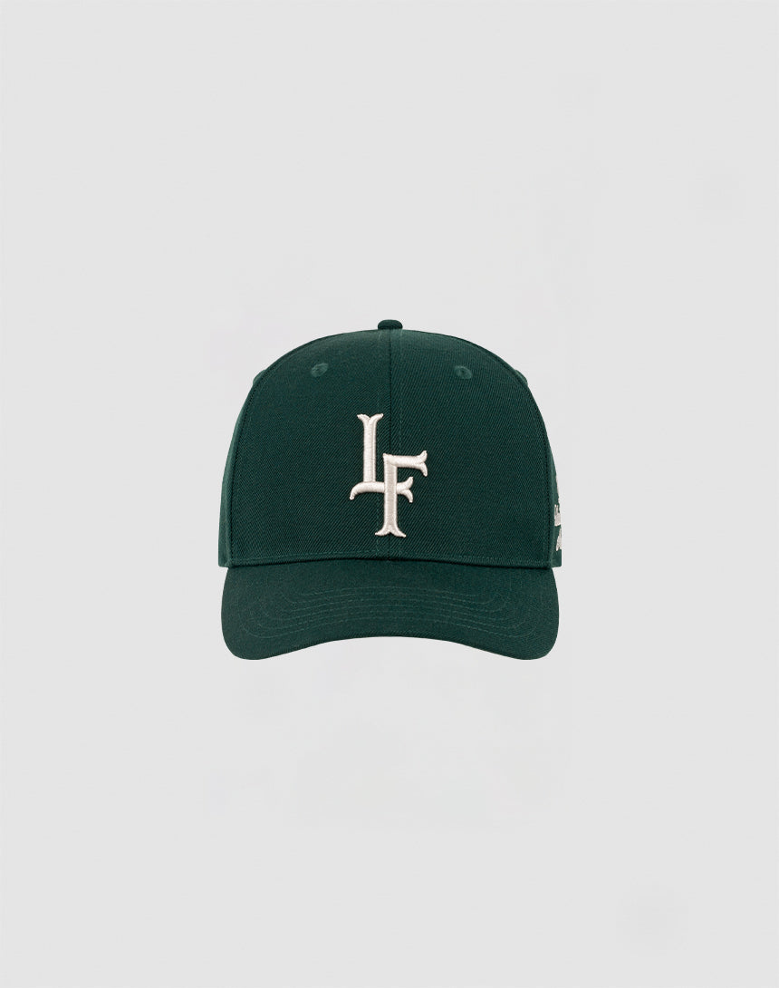 The LF Snapback by LIVE FAST DIE YOUNG is a dark green cap with a bold white LF logo embroidered on the front and a Mit Snapverschluss, shown against a plain light gray background. Model: LF2308-14417.