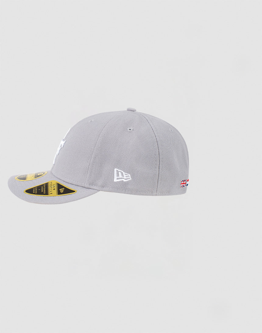The LFDY x NEW ERA 59FIFTY Low Profile Cap by LIVE FAST DIE YOUNG is shown in light grey, with the New Era logo on the left, a small Union Jack near the back, and stickers still on its flat brim.