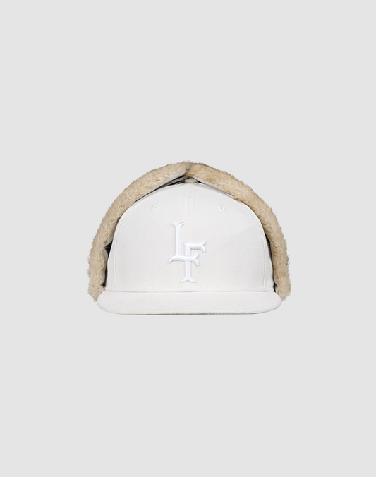 The LFDY x New Era 59Fifty DogEar by LIVE FAST DIE YOUNG is a white fitted cap with beige faux fur lining, and overlapping white embroidered L and F letters on the front, shown against a plain light gray background.