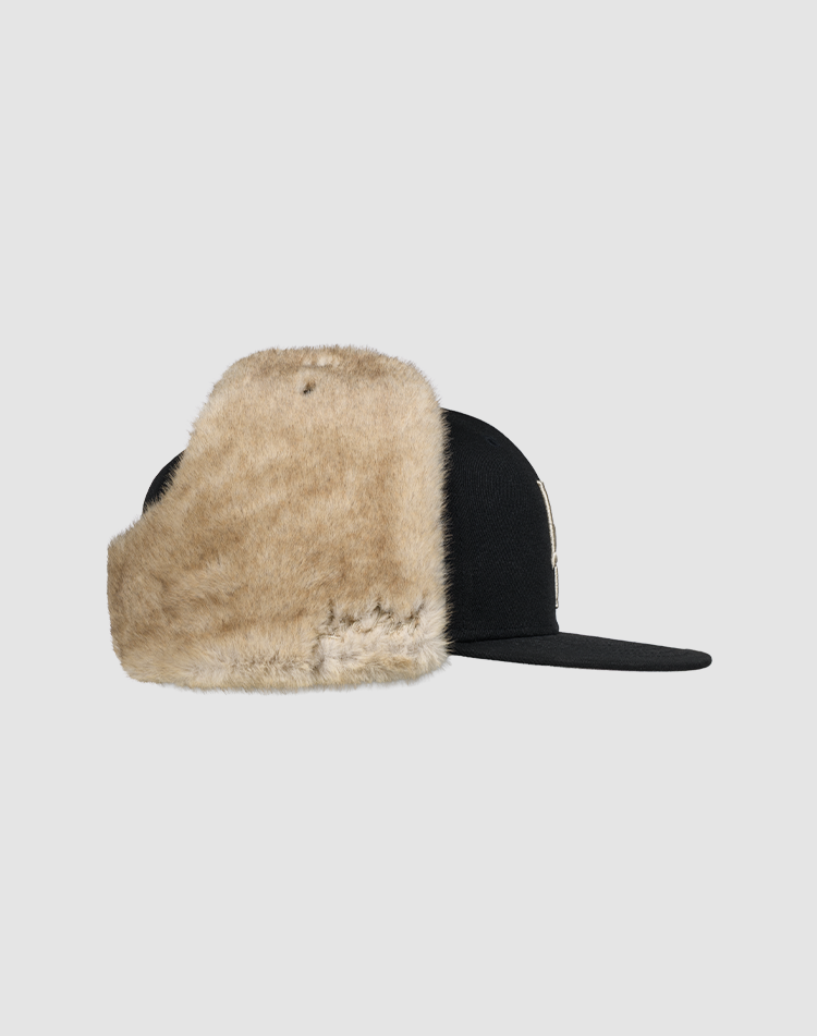 The LFDY x New Era 59Fifty DogEar by LIVE FAST DIE YOUNG features a black fitted cap with flat brim and large beige faux fur logo ear flaps, shown against a light gray background.