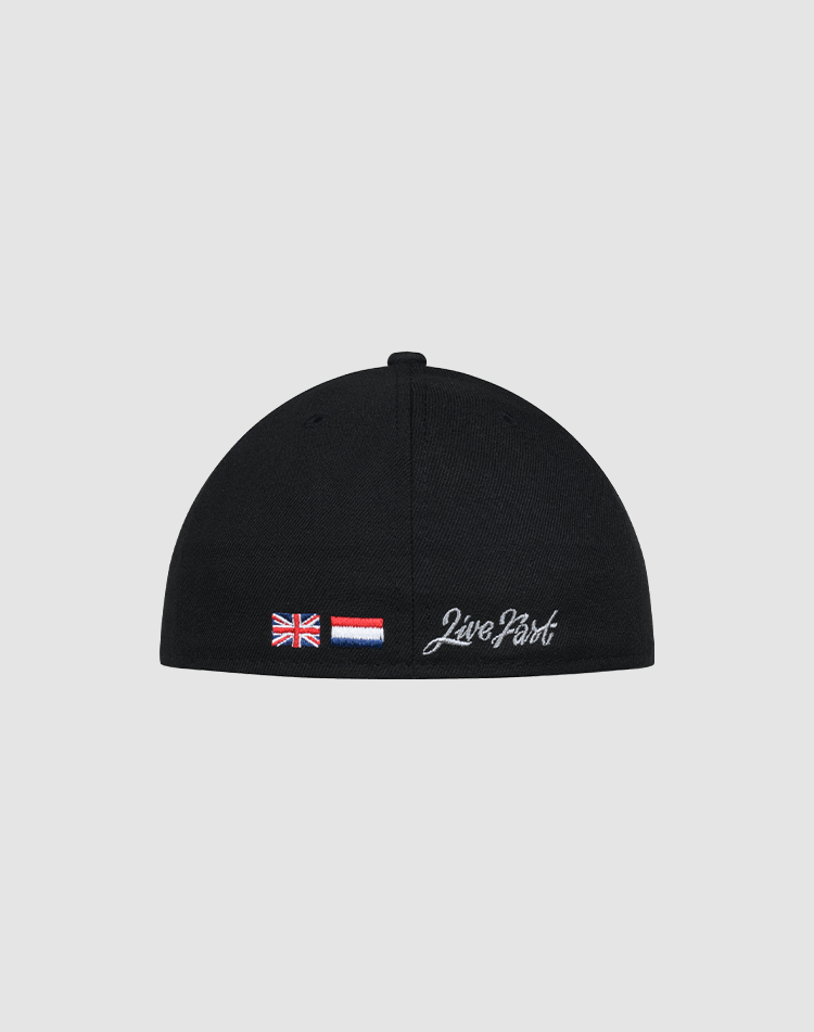 The LFDY X NEW ERA 59FIFTY Low Profile by LIVE FAST DIE YOUNG is a black fitted cap seen from the back, showcasing small British and red-white-blue striped flags plus "Live Fast" in white embroidery—a classic 59FIFTY style.