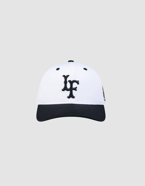 The LFDY Snapback by LIVE FAST DIE YOUNG features a white crown, black brim, black embroidered LF logo on the front, and a classic green underbrim, shown against a plain light grey background. 