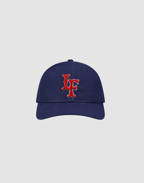 The LFDY Snapback by LIVE FAST DIE YOUNG features a navy blue design with a red and white embroidered “LF” Multi-Logo-Stick on the front, adjustable Snapverschluss, and Modell LF2605-20880. Displayed on a plain light gray background. 