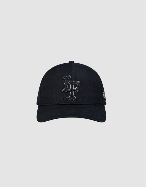 The LFDY Snapback by LIVE FAST DIE YOUNG is a black cap with a curved brim and grey underside, featuring large raised black LF initials on the front, a small white Multi-Logo-Stick on the left, and a practical snap closure. 