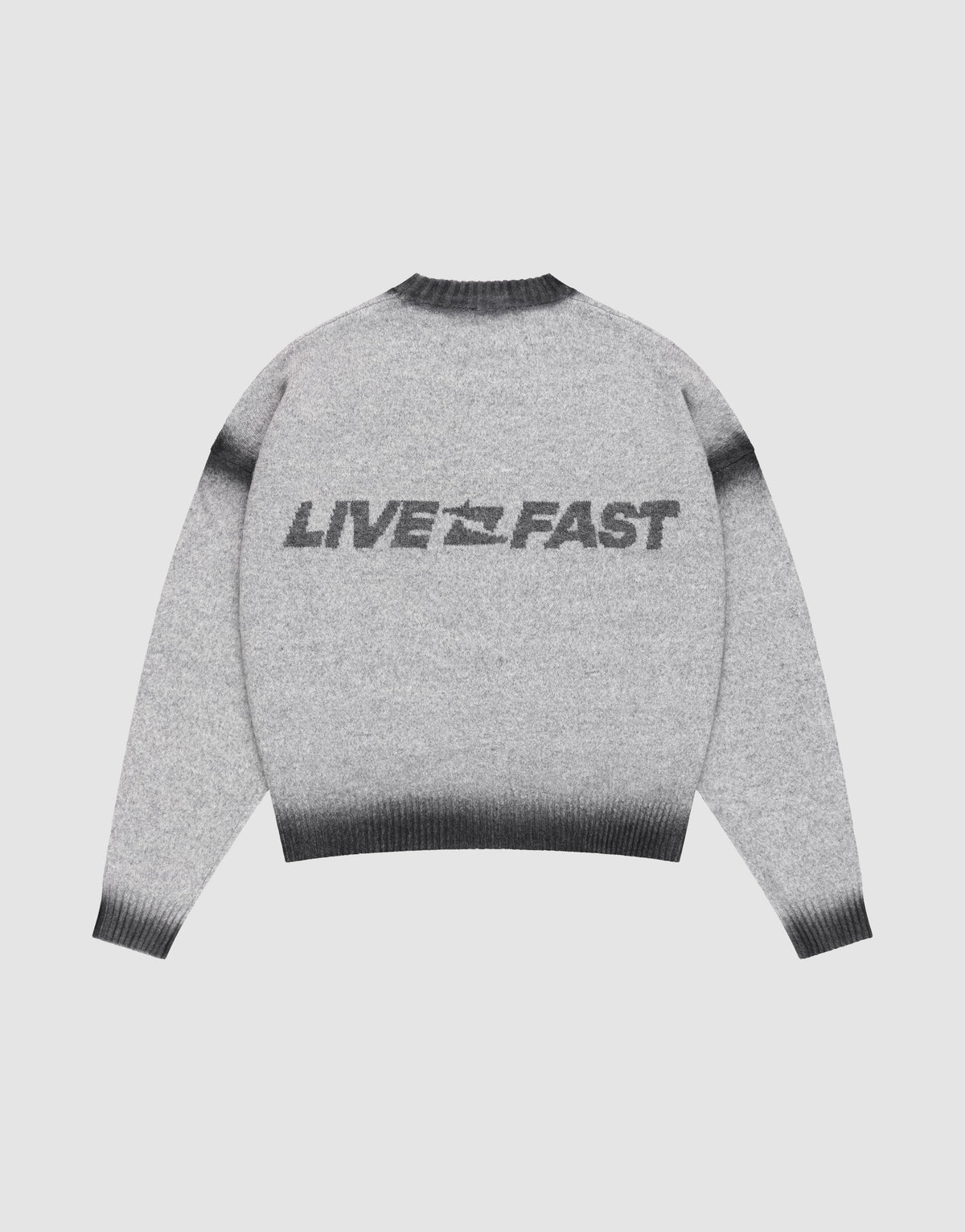 The LIVE FAST DIE YOUNG Live Fast Boucle Sweater features an oversize fit, gray tone, dark gradient cuffs, hem, and collar in a faded spray effect. "LIVE FAST" with a lightning bolt is printed bold on the back. Shown laid flat on a plain background.