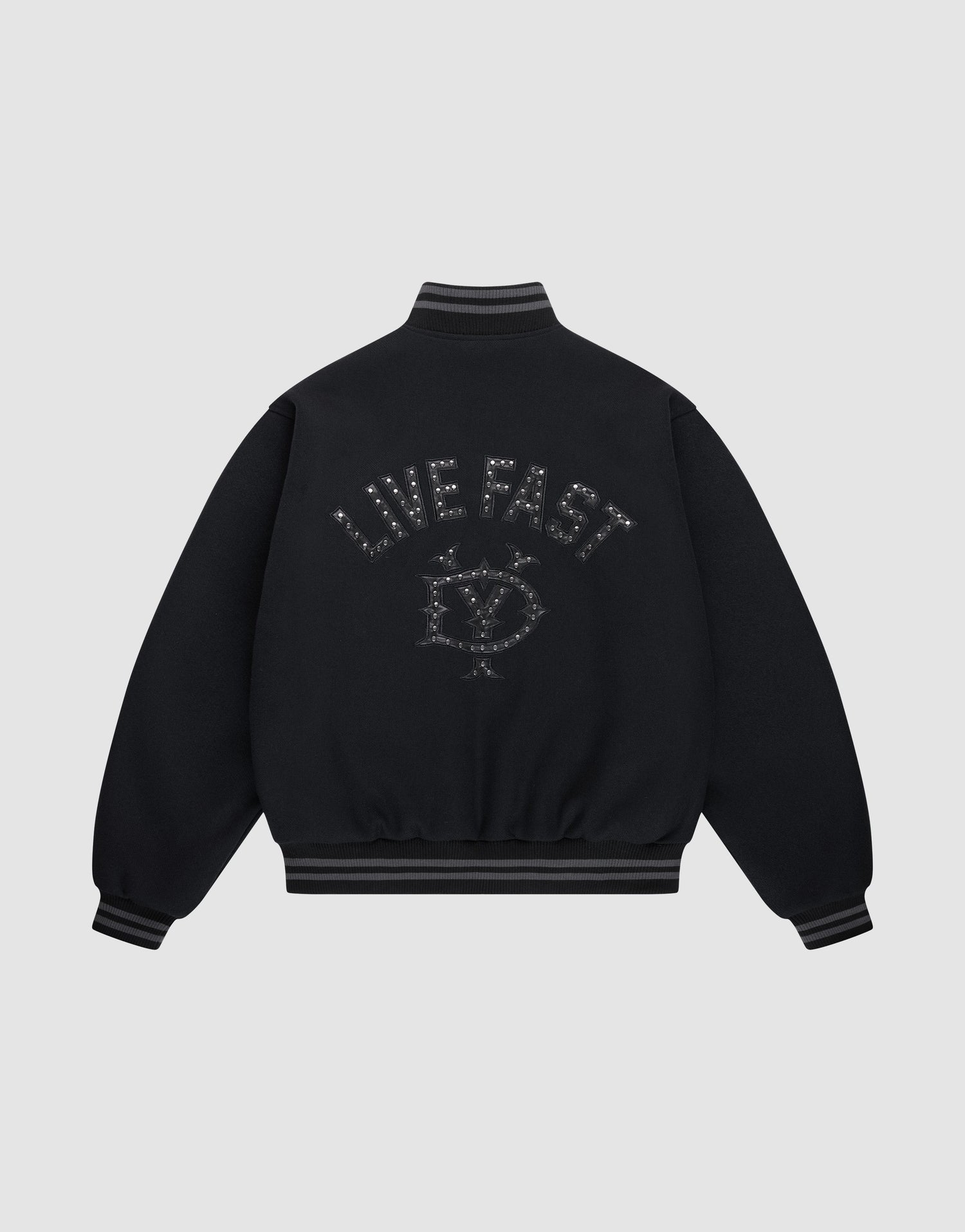 The Live Fast College Jacket by LIVE FAST DIE YOUNG is a black varsity jacket with striped cuffs and hem, a metal zipper, and an embroidered eye with stars and "LIVE FAST" on the back in dark thread. The background is light gray. | plain