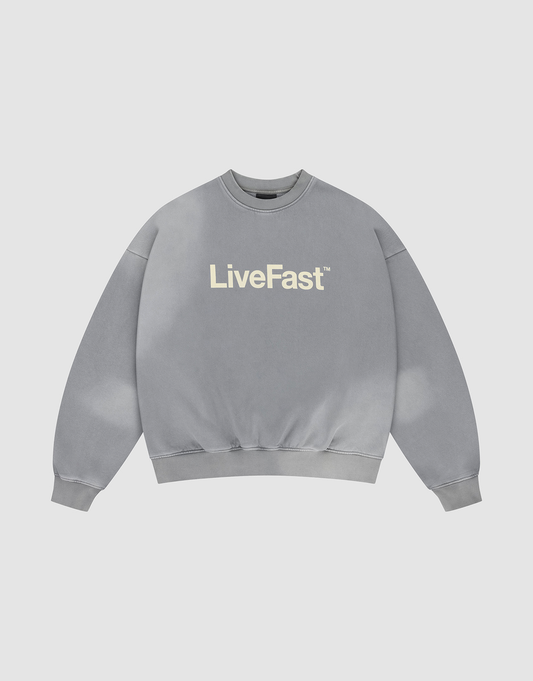 The Basic LiveFast Sweater by LIVE FAST DIE YOUNG is a gray, oversized crewneck with “LiveFast” in bold white on the chest and a subtle handgefertigter Fade-Effekt, shown laid flat on a plain light background. | plain