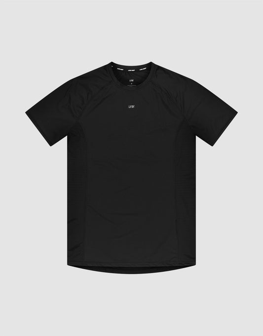 The LFDY Performance Slim Tee by LIVE FAST DIE YOUNG is a black slim-fit, short-sleeve athletic t-shirt with a crew neck and a small white reflective logo print at the center chest, shown against a light gray background. | plain
