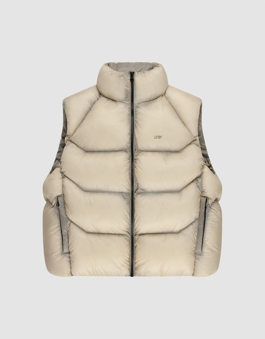 The Live Fast Puffer Vest by LIVE FAST DIE YOUNG features a beige color, high collar, black front zipper, two zippered side pockets, and an oversize fit, shown against a plain light gray background. | plain