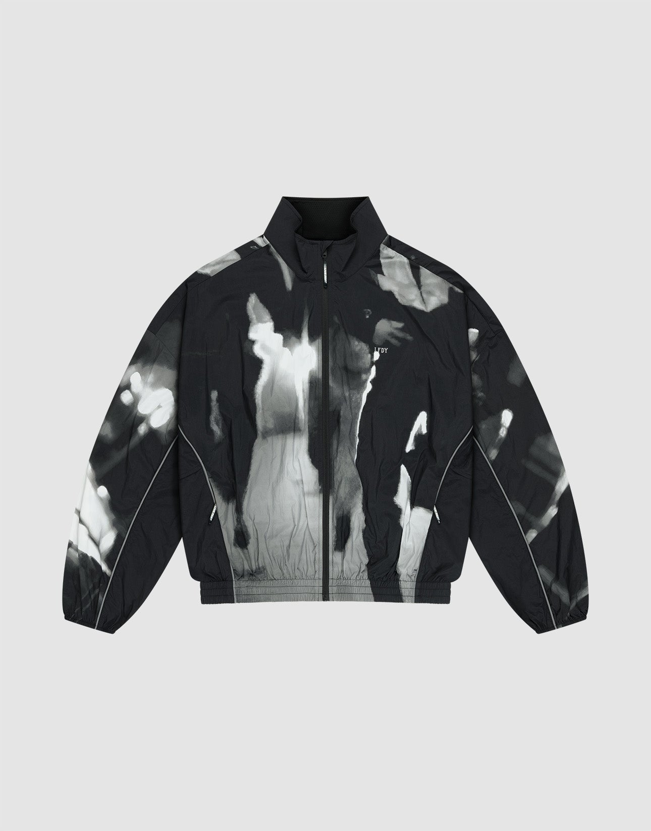 The LFDY Performance Jacket by LIVE FAST DIE YOUNG features a black and white zip-up nylon design with a high collar and abstract tie-dye-style allover print on a gray background.