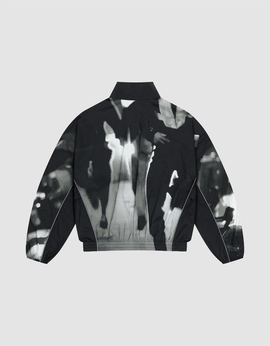 The LFDY Performance Jacket by LIVE FAST DIE YOUNG is a black nylon piece with long sleeves, a collar, and an abstract high-contrast black and white print of blurred human figures on the back, shown on a plain light gray background.